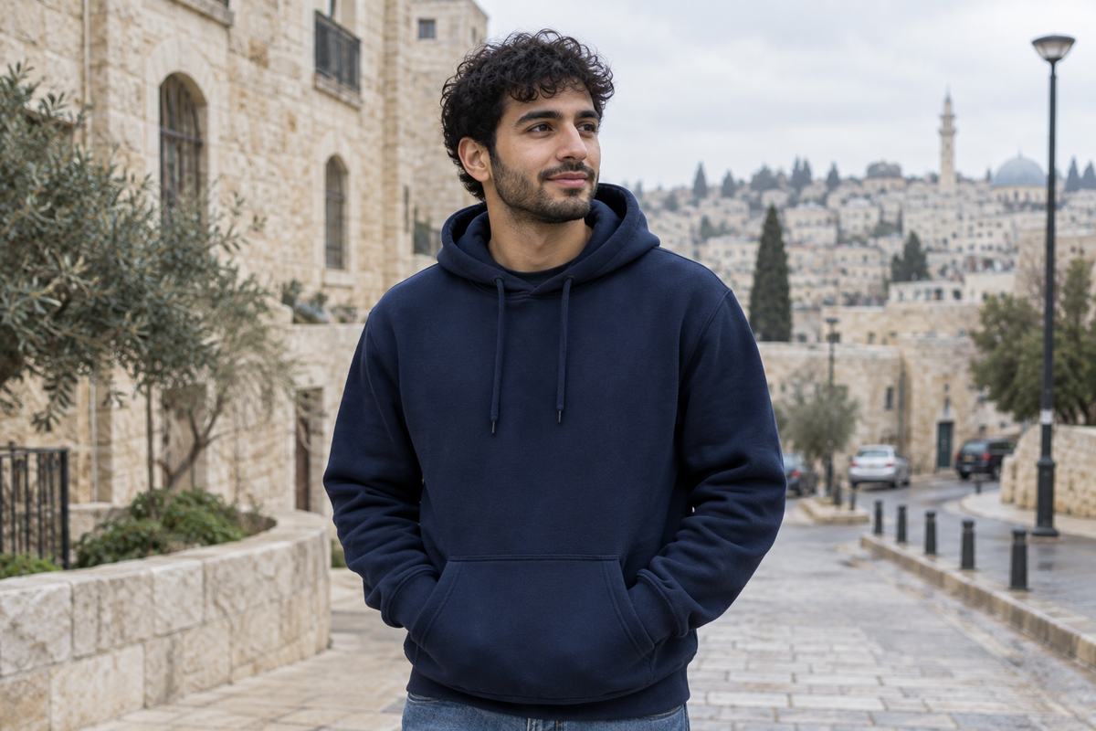 شاب يرتدي هودي كحلي سادة للشتاء من الأردنية المعاصرة لصناعة الألبسة في شارع عربي | Young man wearing a plain navy winter hoodie by Jordanian Modern Textile on a Middle Eastern street